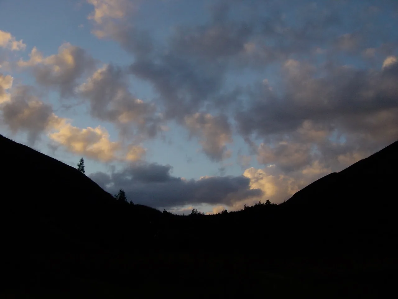 Silhouettes sombres des terrils jumeaux sous un ciel nuageux